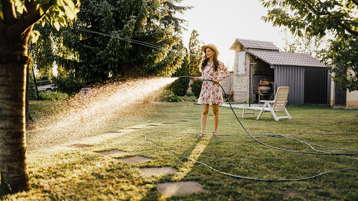 young woman water lawn with hosepipe