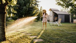 young woman water lawn with hosepipe