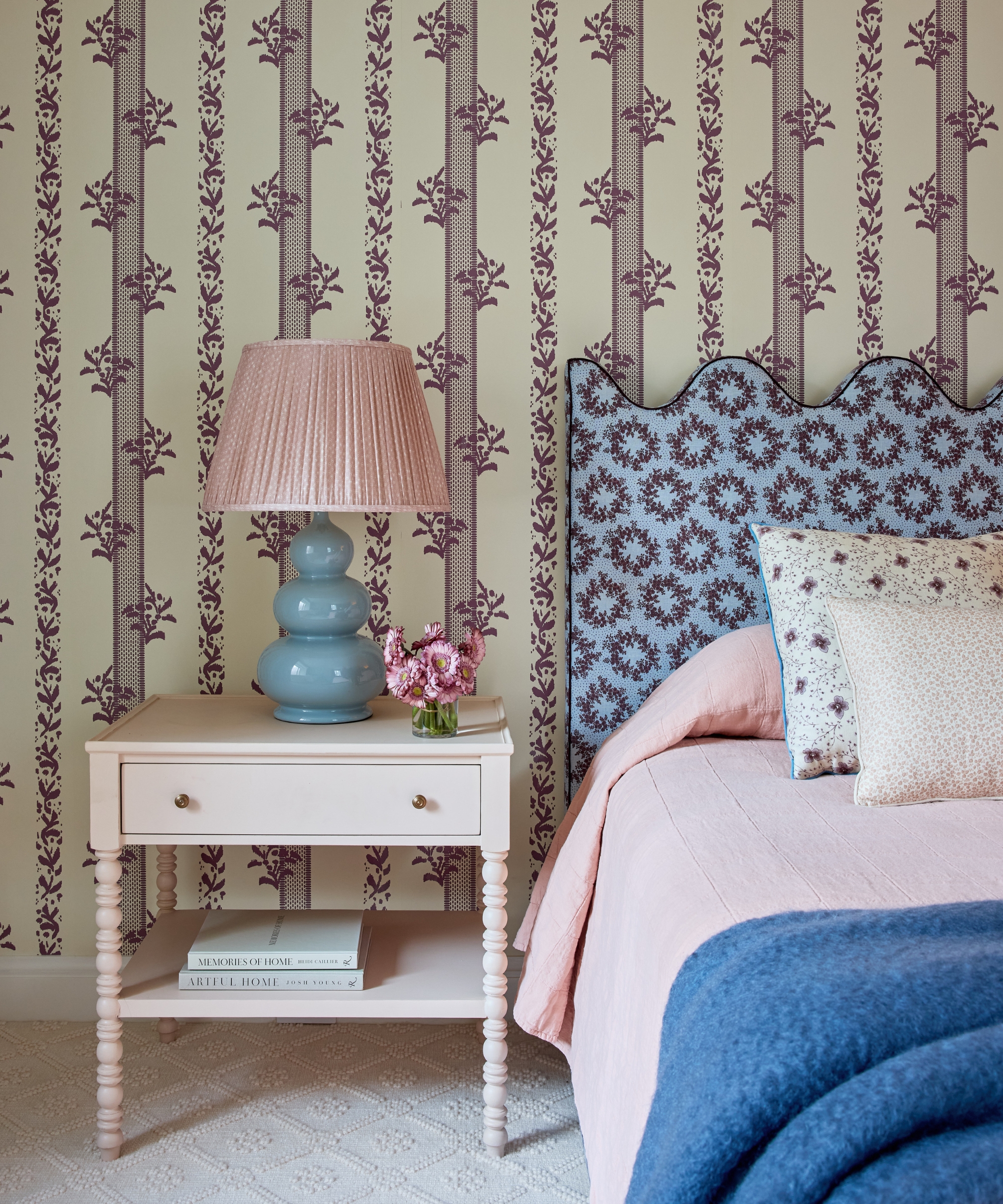 Girl&amp;rsquo;s bedroom with floral wallpaper, bespoke scalloped bed, bobbin bedside table and blue ceramic lamp.