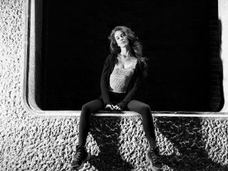 Black and white portrait of a person sitting on a concrete wall