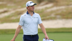 Justin Thomas walks down the fairway holding his yardage book