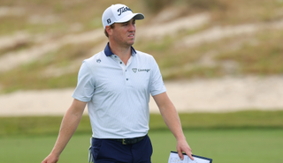 Justin Thomas walks down the fairway holding his yardage book