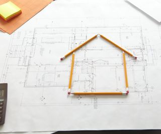 architect plans with house outline on top made from pencils