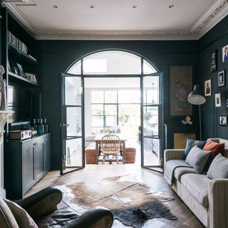 Black living room with arched glass doors leading to open plan dining and kitchen