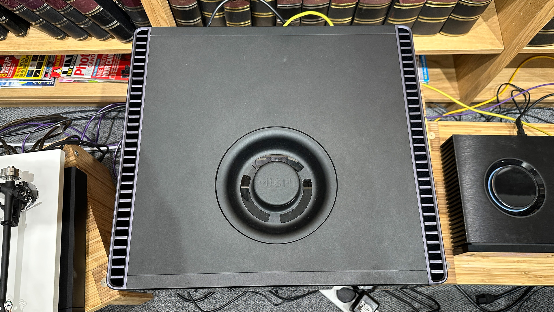 Rotel Michi Q5 CD player on wooden hi-fi rack in front of bookcase, top down view with CD lid in place