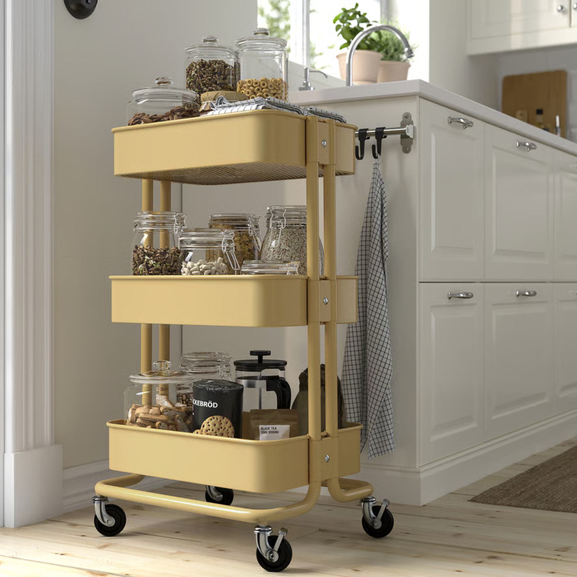 RÅSKOG trolley in butter yellow holding jars of spices in a kitchen.