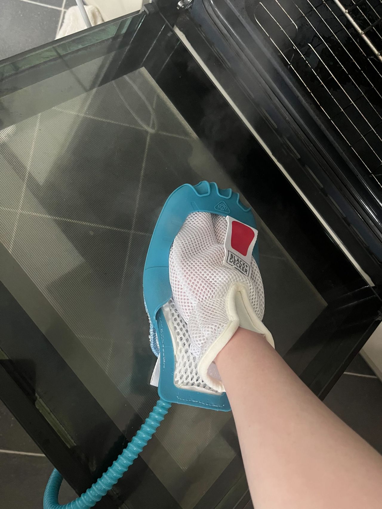 A steam cleaning mitt being used to clean a glass oven door