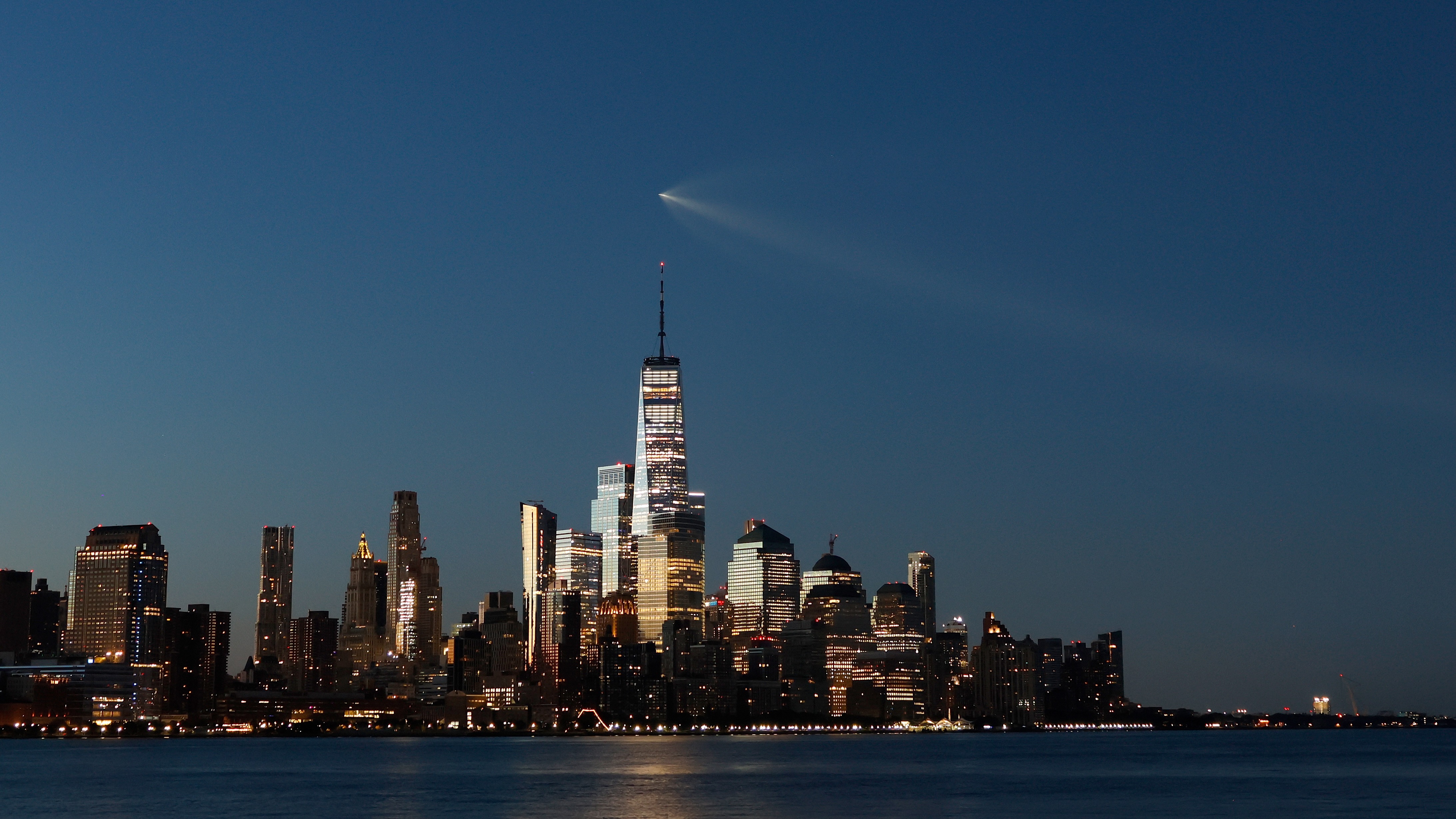 A SpaceX Falcon 9 rocket on mission Starlink Group 10-49 passes by lower Manhattan and One World Trade Center just before dawn in New York City after launching from Cape Canaveral, Florida on Aug. 25, 2026, as seen from Hoboken, New Jersey.