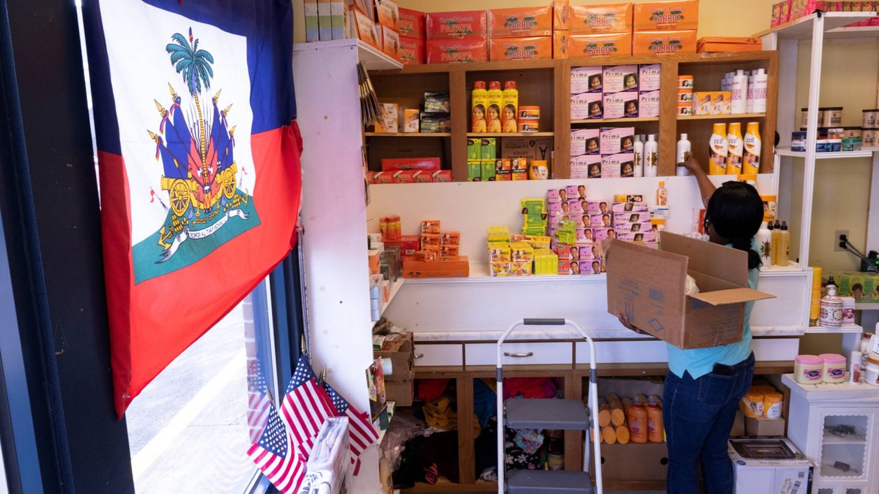 Haitian American Philomene Philostin stocks the shelves of her store in Springfield, Ohio.