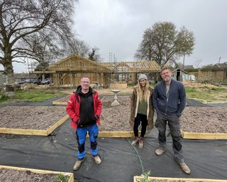 Mark Millar with couple Lucy and Mike stood in front of timber frame structure