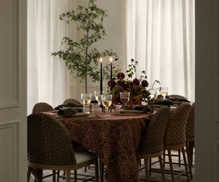 Fall table with a deep red tablecloth and a seasonal flower arrangement