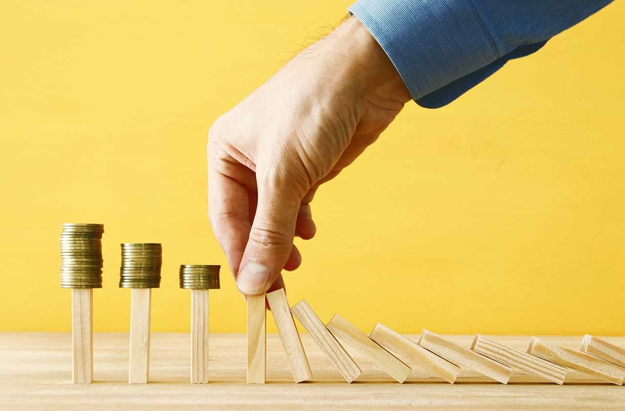 concept image of investing and banking. A businessman stops the domino effect from risking financial investment