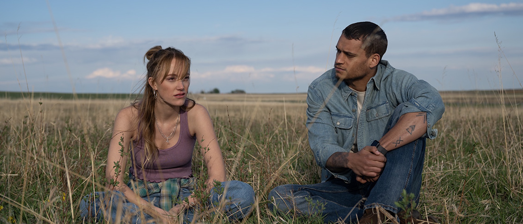 Maika Monroe and Tyriq Withers sitting in a field together in Reminders Of Him 