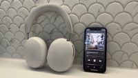 The Sonos Ace headphones next to an iPhone 12 Mini playing Oasis in Spatial Audio on Apple Music.