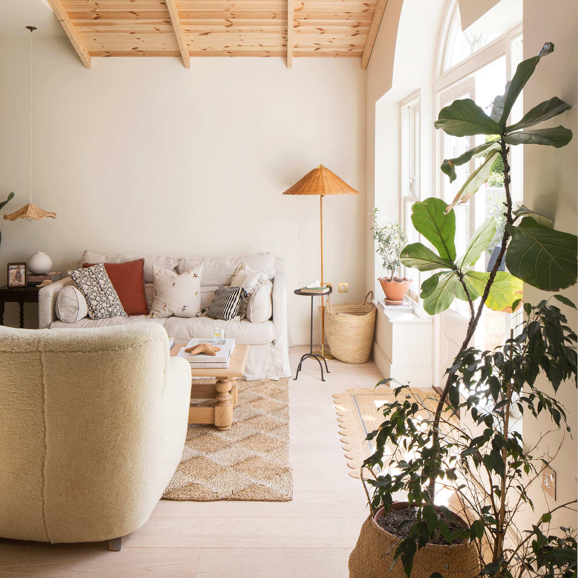a large neutral living area with patio doors cream sofas and wooden armchairs, and a wooden clad ceiling