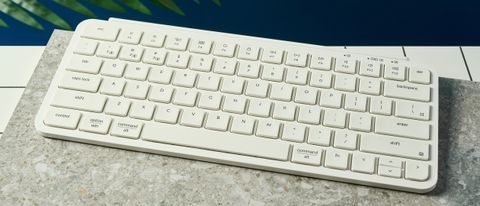a white wireless bluetooth keyboard resting on a clean white table close up shot shows the white keys