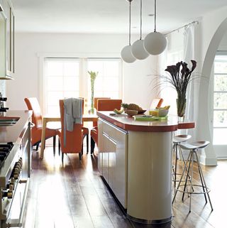 kitchen dinning area white wall white counter dinning table with orange chairs and wooden floor