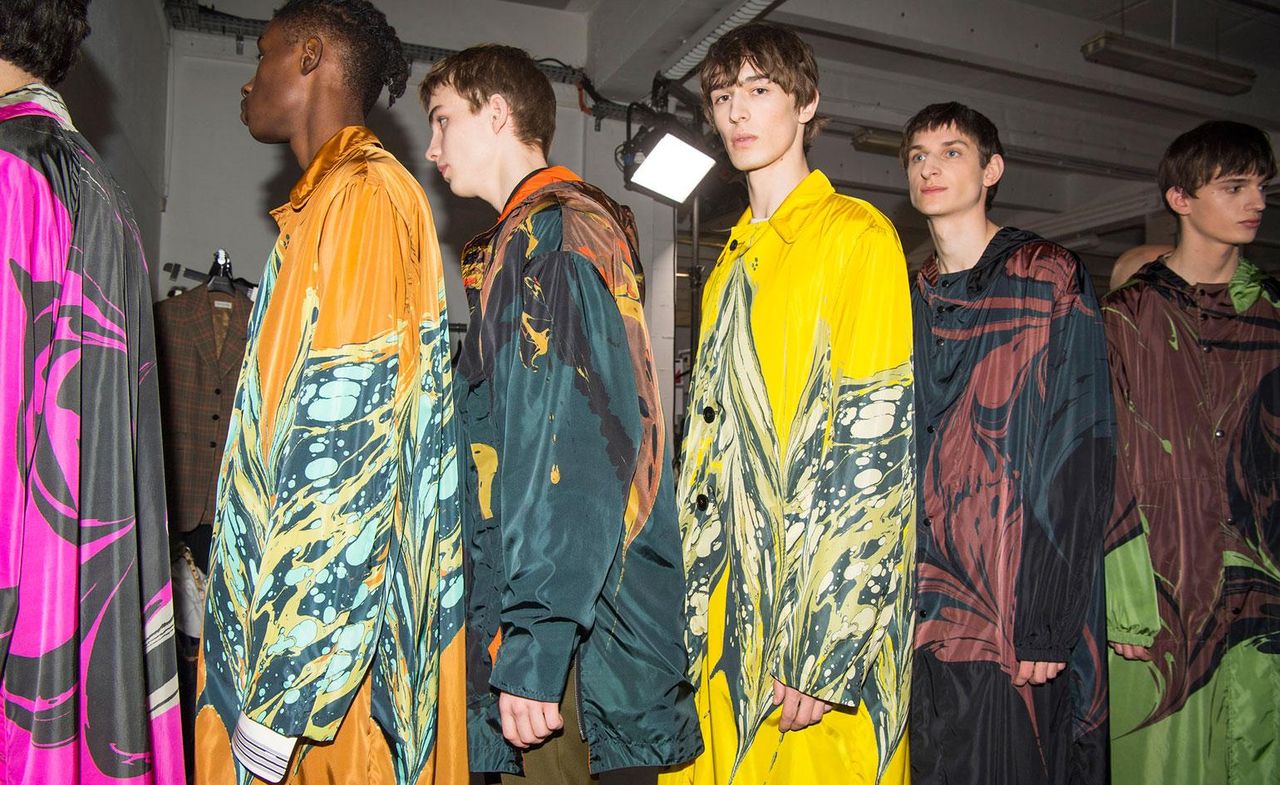 6 male models stood in a line wearing long colourful coats