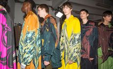 6 male models stood in a line wearing long colourful coats