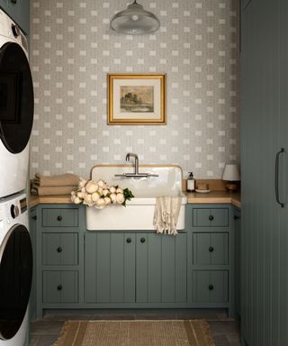 laundry room with dark green cabinets, light gray wallpapered walls and rustic details