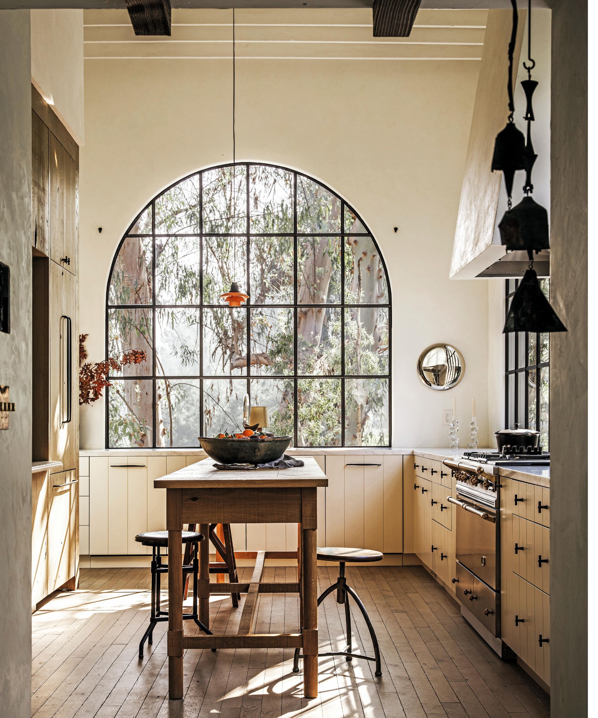 a large neutral kitchen with large arched crittal windows, paneled kitchen with a small wooden island