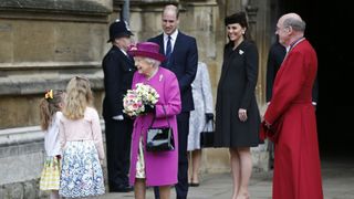 Queen Elizabeth II smiles as she receives flowers from two girls as Catherine, Princess of Wales, Prince William and Dean of Windsor, David Conner (R) look on after they attend the Easter Service