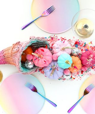 A rainbow cornucopia thanksgiving centerpiece with pastel colored plates and iridescent cutlery