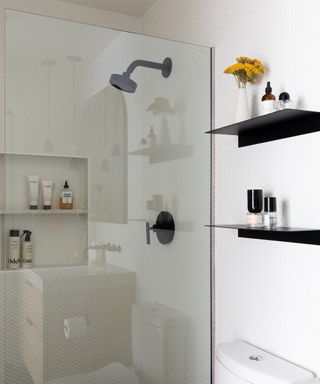 A white bathroom with white tiled walk-in shower and black shower hardware