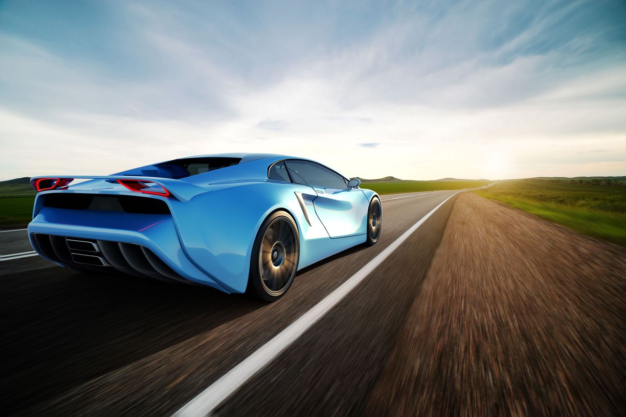 A blue sports car drives down the road. 