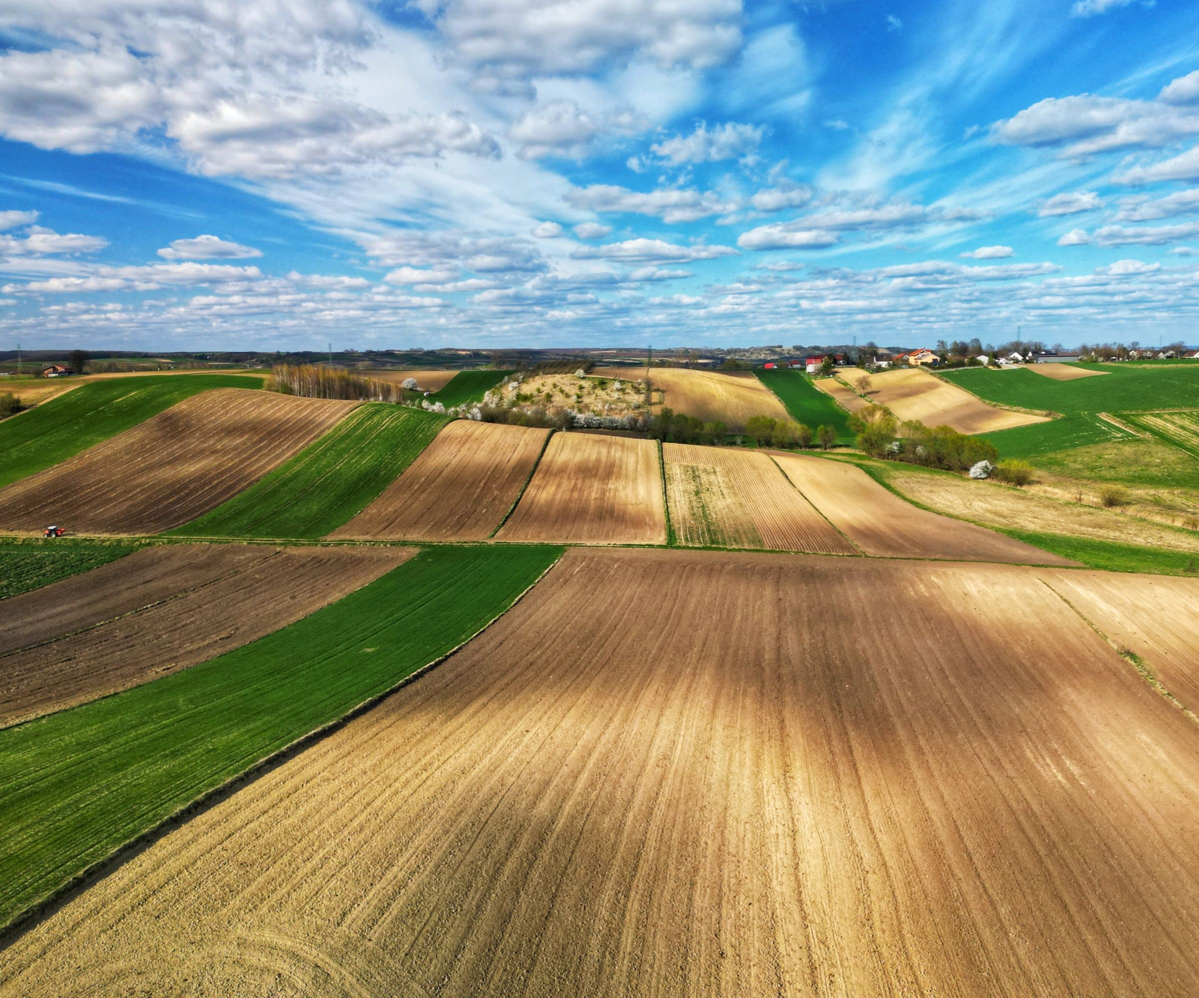 Fields on hills with a bright blue sky with clouds above