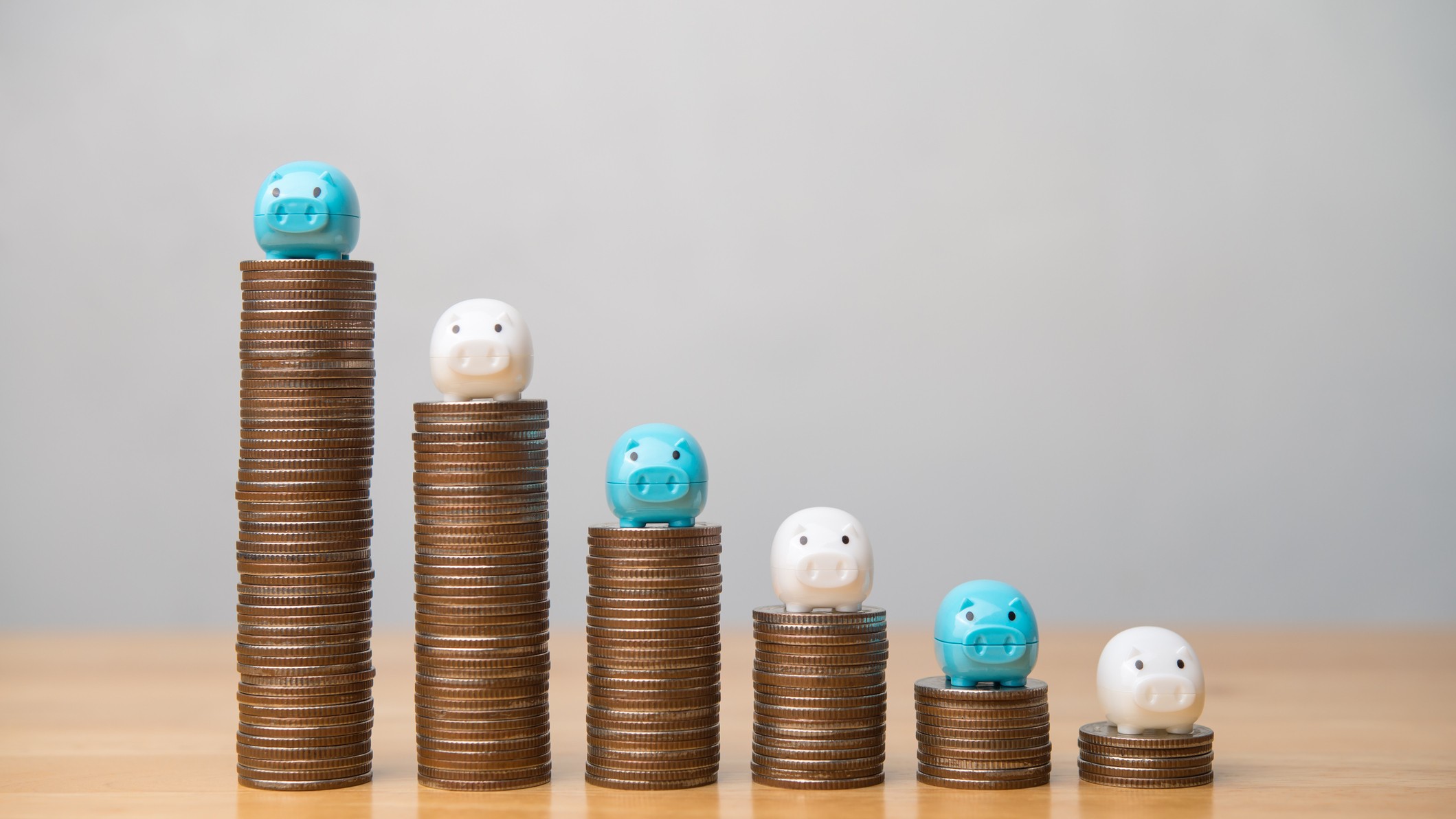 Piggy bank on top of drop stack coins chart with white wall background copy space. Savings reduction in economy crisis such as inflation, recession, loss investment, bankruptcy, overburdened concept.