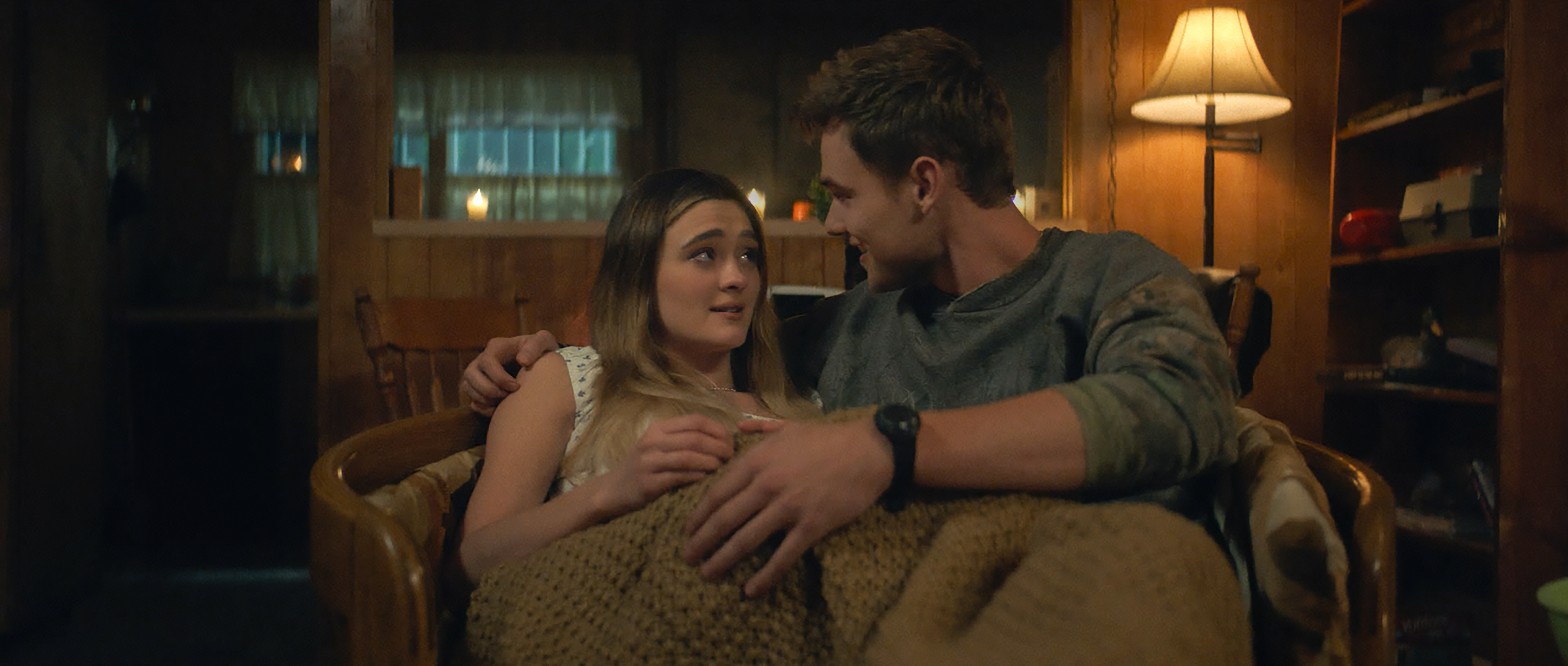 Lizzy Greene as Lauren and Garrett Wareing as Lucas sitting under a blanket in a cozy chair together cuddling in a still from ransom canyon season 2