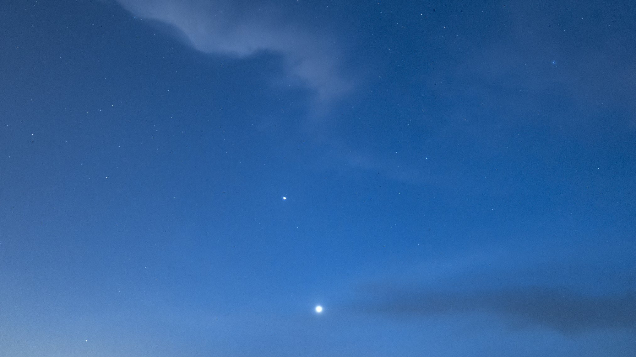 Темно-синее небо с пушистыми облаками и двумя яркими точками света: Венера и Меркурий.
