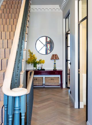 Small entryway with blue walls, sisal rug and round mirror