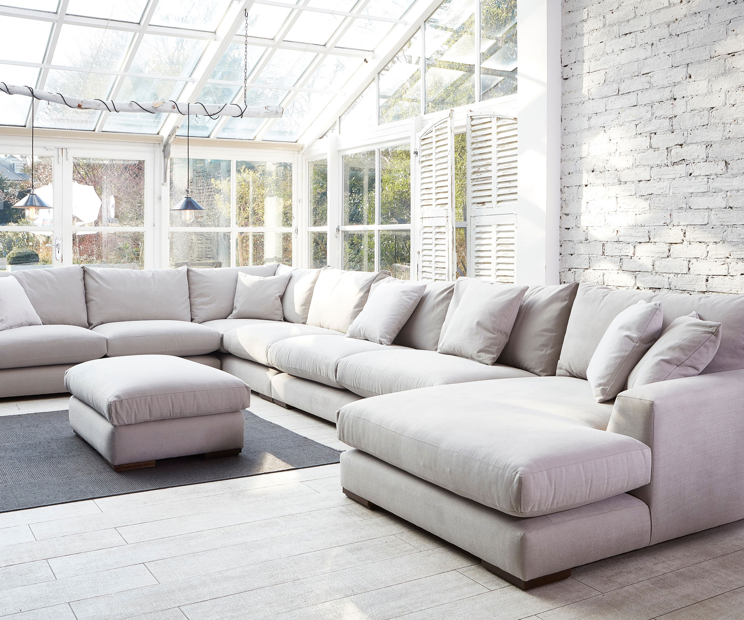 large conservatory living room with shutters and exposed white brick