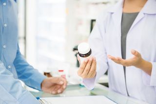 A pharmacist handing a bottle to a patient.