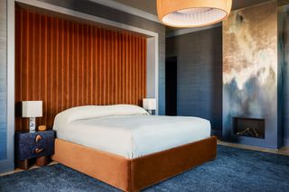 The renovated bedroom with a wall mural detail and paneled headboard wall