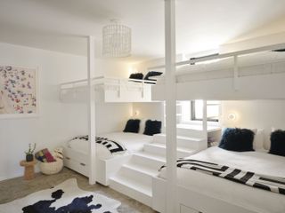 Guest bedroom with 4 queen sized bunk beds, white decor