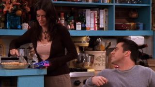 Joey (Matt LeBlanc) watches Monica (Courteney Cox) cut him a slice of pie on Friends.