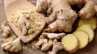 Whole ginger, cut pieces of ginger, and powdered ginger on a bench