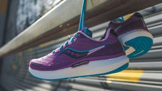 Saucony Triumph 19 running shoes in pink hanging from a metal rail