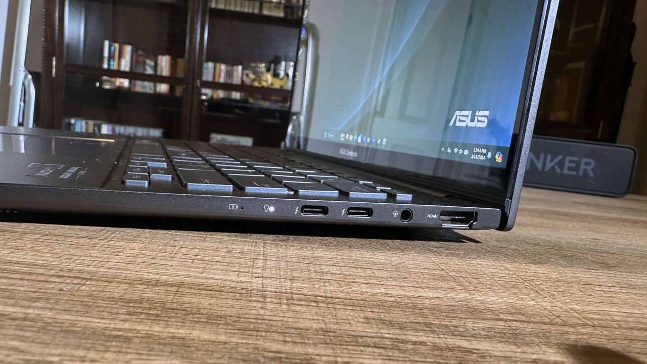 Sideview of Asus Zenbook 14 OLED (Q425M) open on a wooden desk to show ports and overall thinness