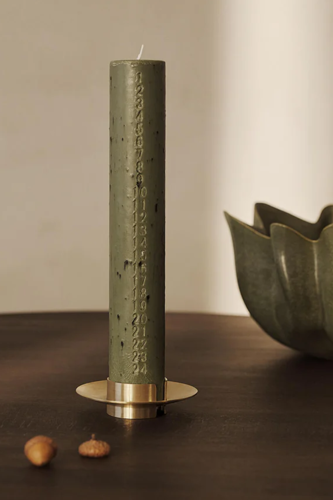 A green taper advent candle on a gold holder