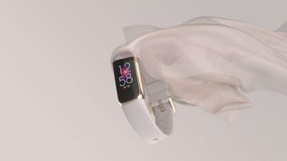 Fitbit Luxe: An image showing the tracker in white with a sateen sheet flowing from its side