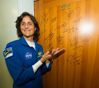 Expedition 32 NASA Flight Engineer Sunita Williams smiles for the camera after signing one of the doors at the Cosmonaut Hotel in a tradition.