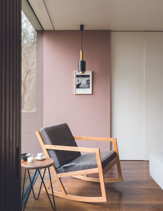 A pink painted room with a wooden chair
