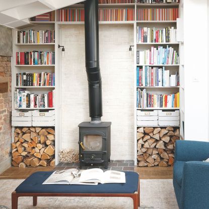 Log burner in seating area, with bookshelves either side and log storage at the bottom
