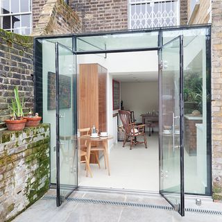 Glass extension at back of house with chairs and table inside