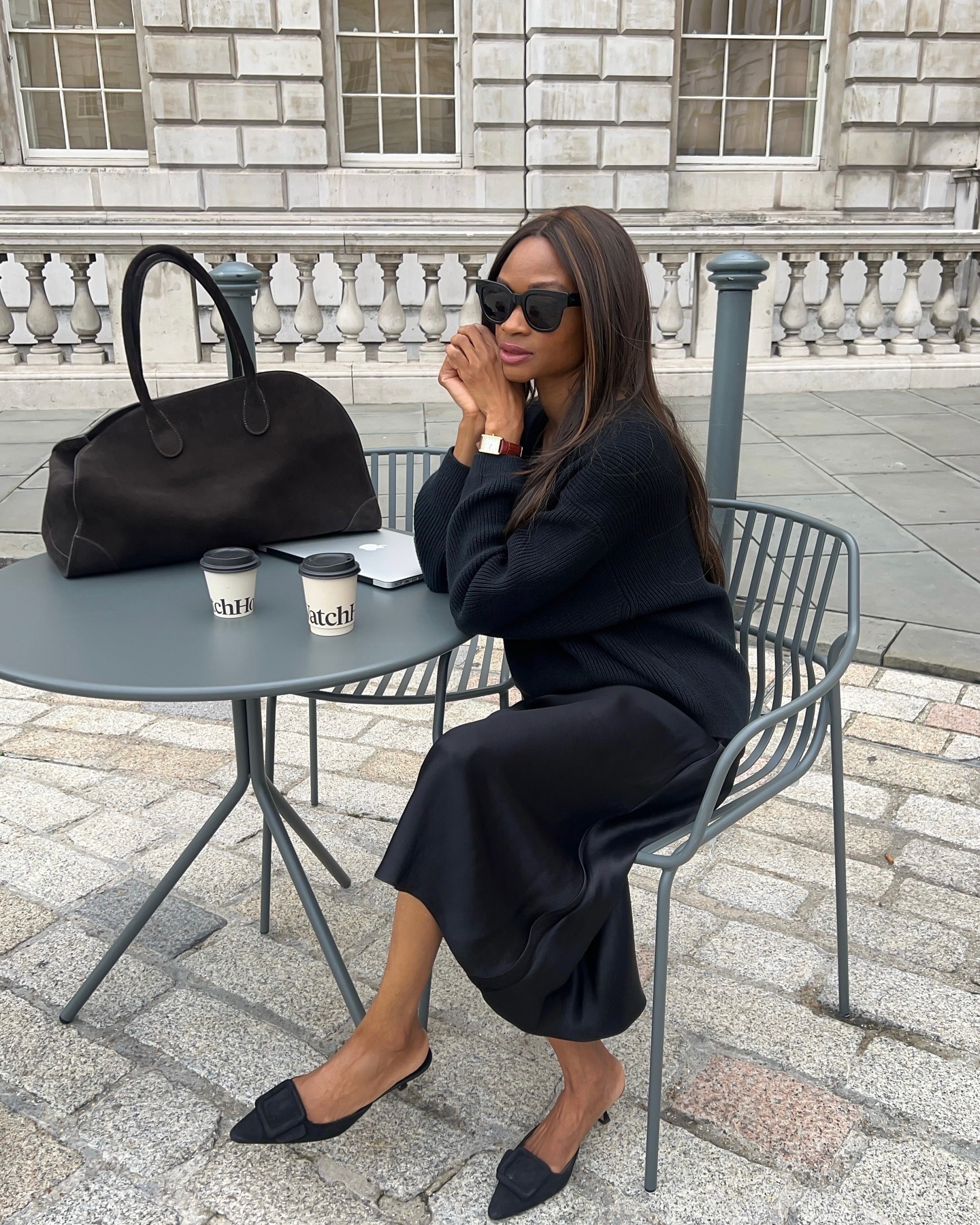 Influencer @lornasymphony wears a navy jumper and navy silk skirt with a brown suede handbag.