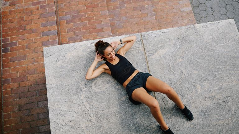 Woman lying on the floor practicing how to do a crunch with perfect form